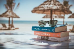 um óculos em cima de uma pilha de livros em uma mesa na praia